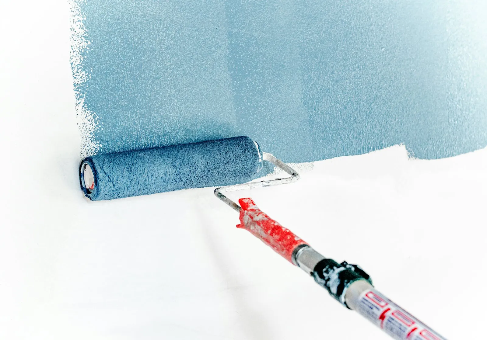 Paint roller rolling blue paint onto a wall