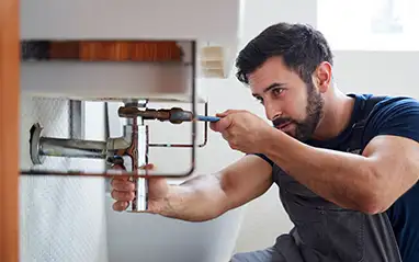 Plumber repairing pipework under a bathroom sink